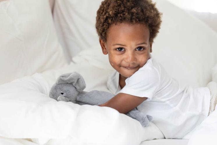 3 year old laying in bed smiling