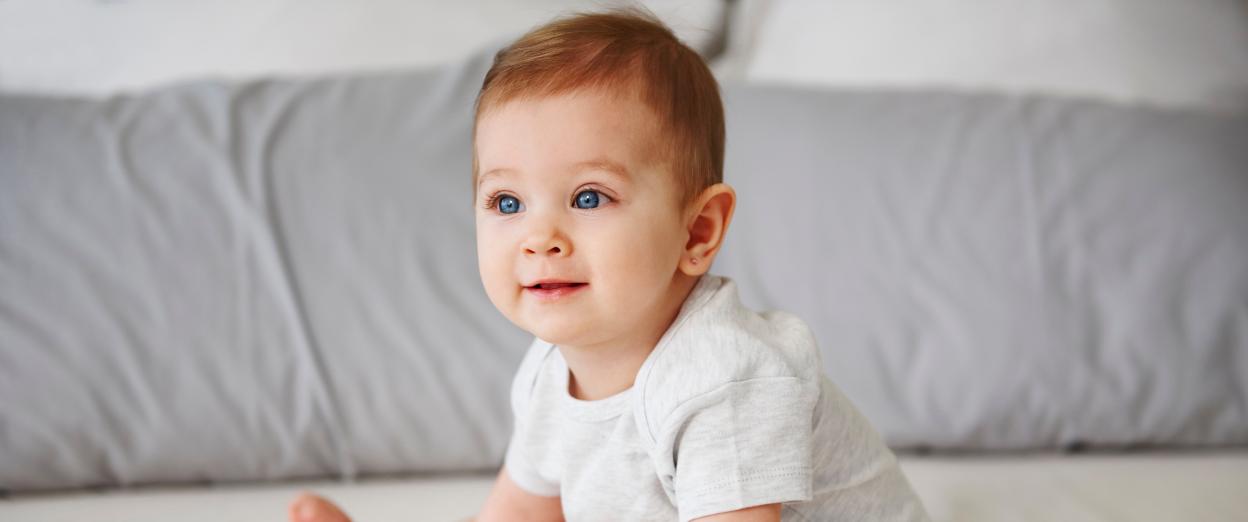 seven month old sitting up looking away from camera