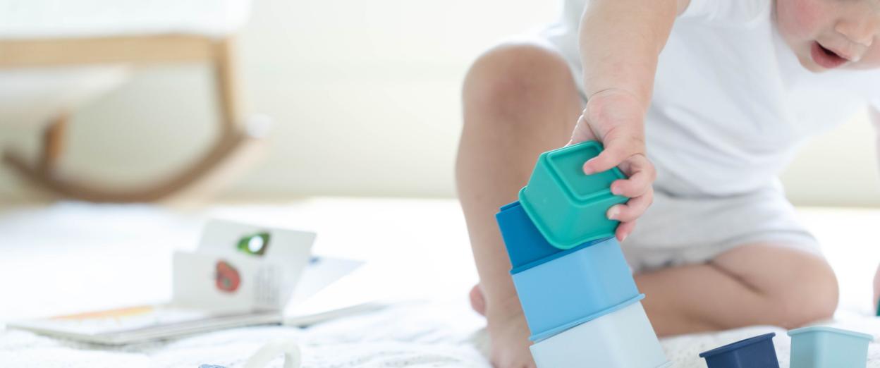 baby sitting playing by stacking square silicone containers