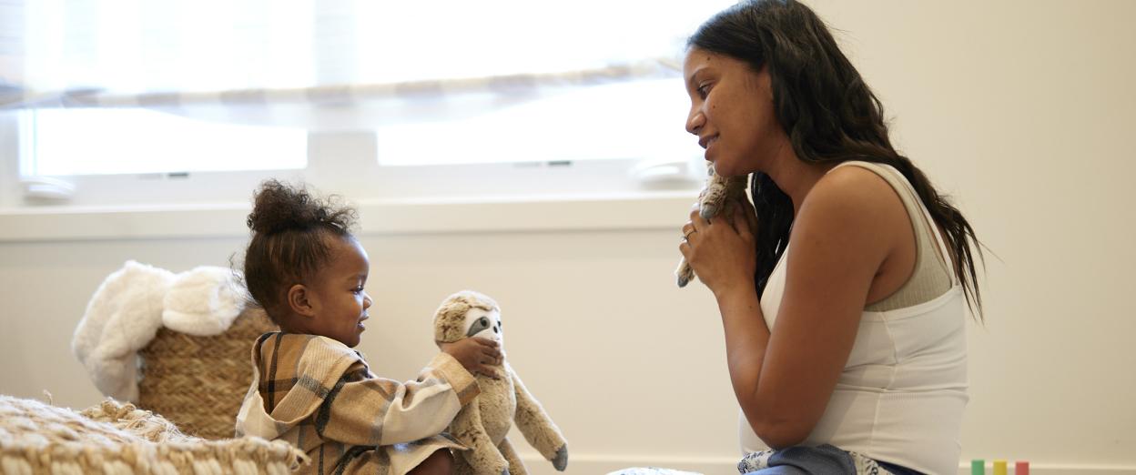Mom and toddler playing together happily with stuffed animals