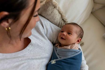 happy swaddled baby in mom's arms