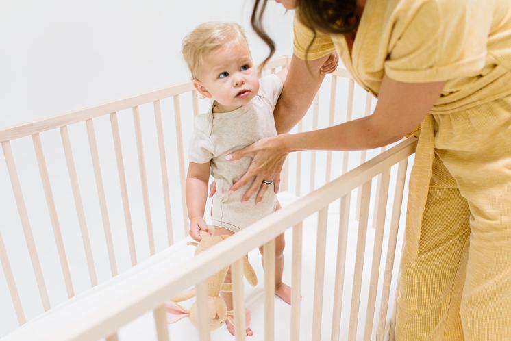mom trying to put older baby with separation anxiety into crib with her lovey