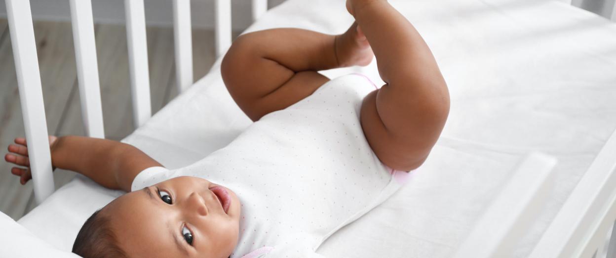 Baby laying in crib with arms extended
