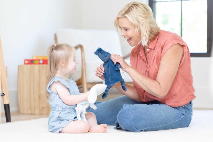 woman and child sitting smiling and holding loveys