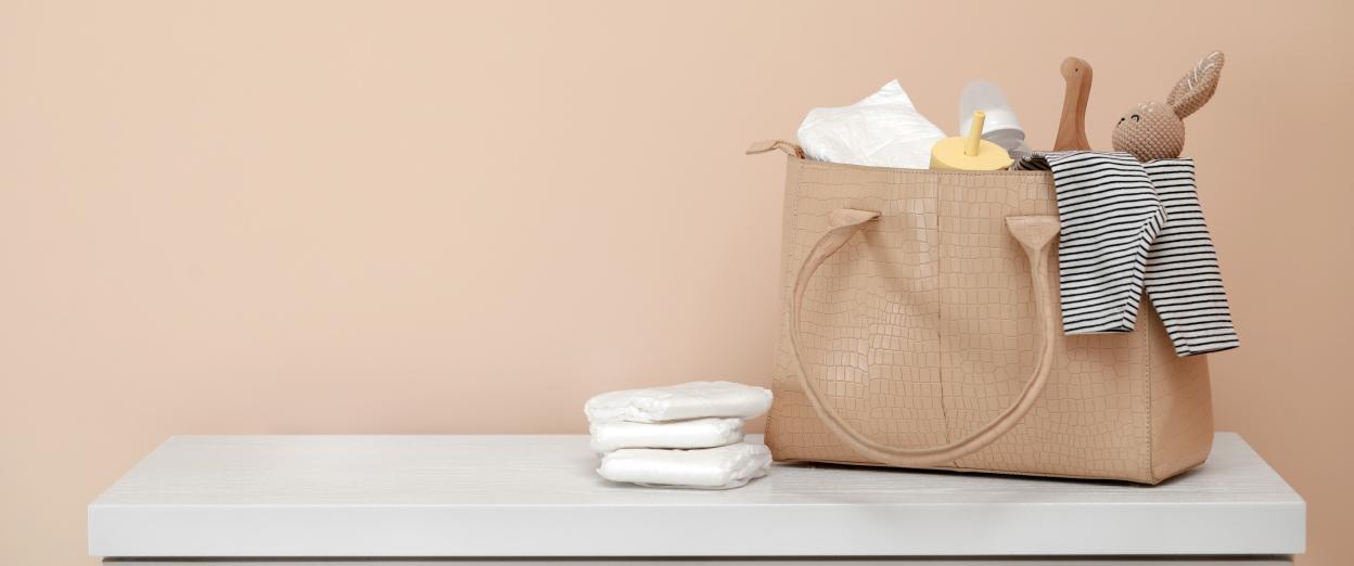 diaper bag ready to be reloaded sitting on dresser against a tan background