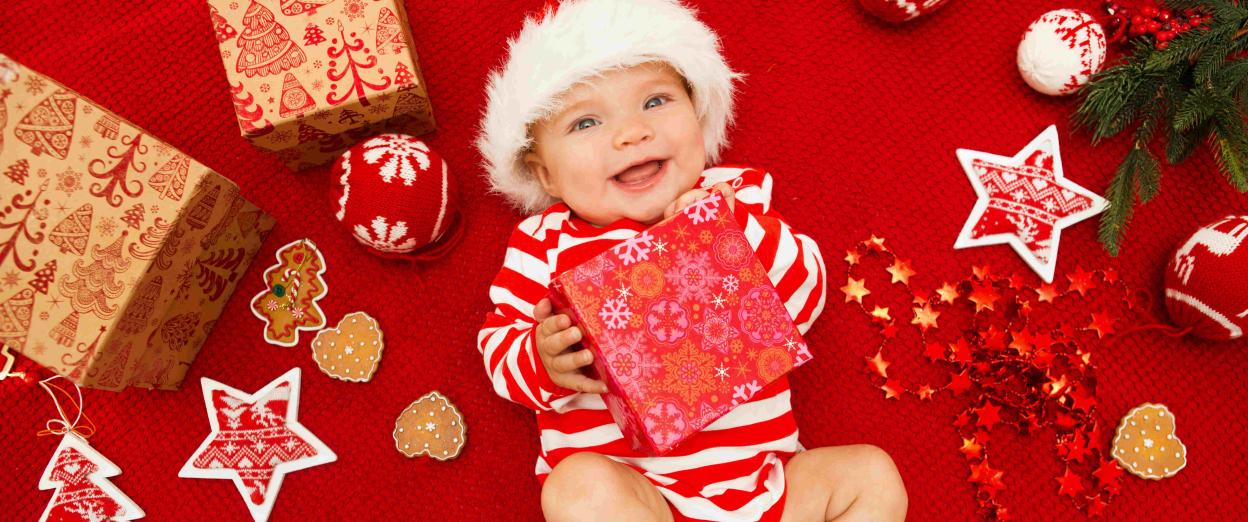 baby wearing santa hat and holding christmas present