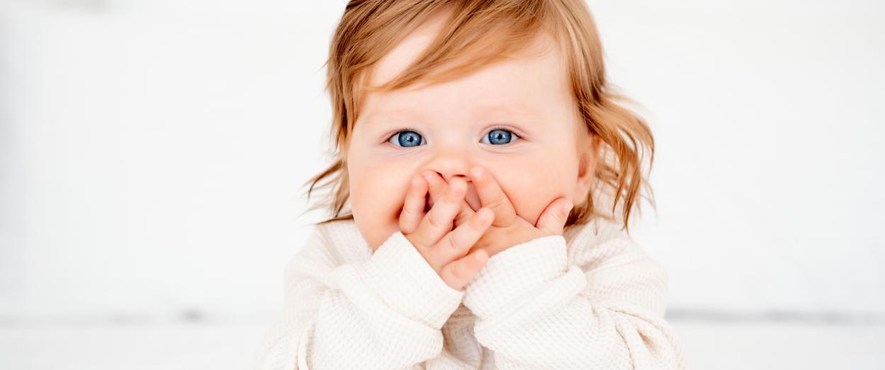 FOMO baby staring at camera with hands over mouth awake