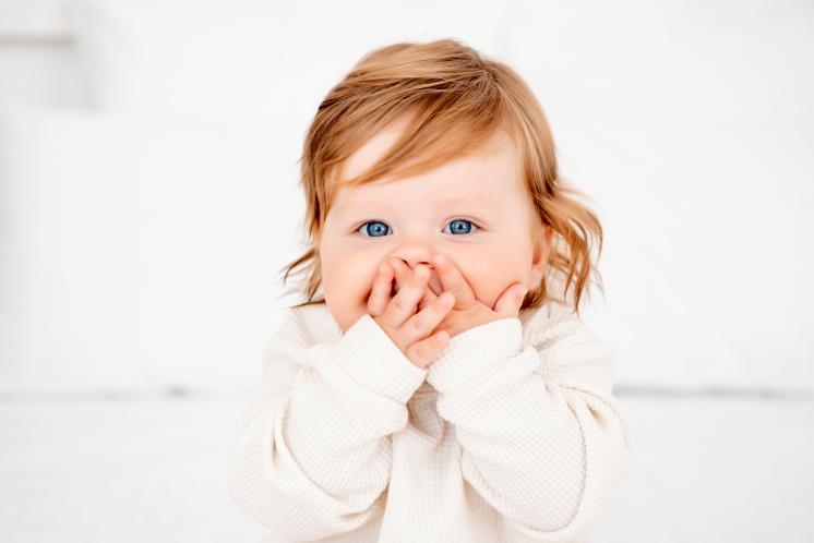 FOMO baby staring at camera with hands over mouth awake
