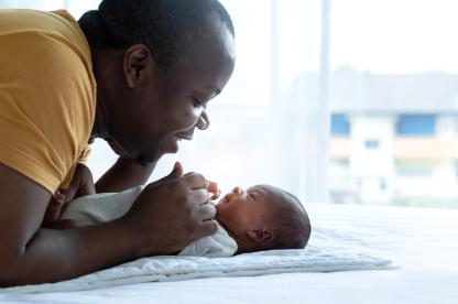 father having face to face time with newborn baby laying on a white blanket