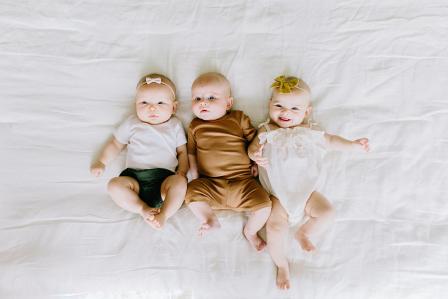 three three month old babies actively looking around and smiling at the camera