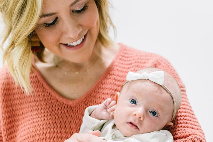 Cara holding newborn baby looking down at her