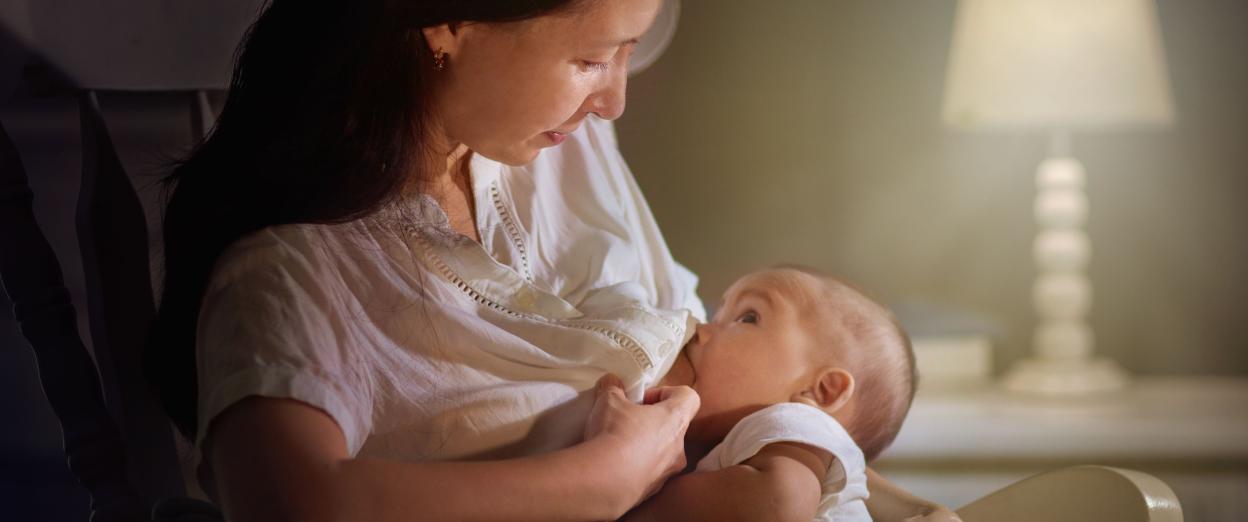 mom in rocking chair nursing baby in the dark