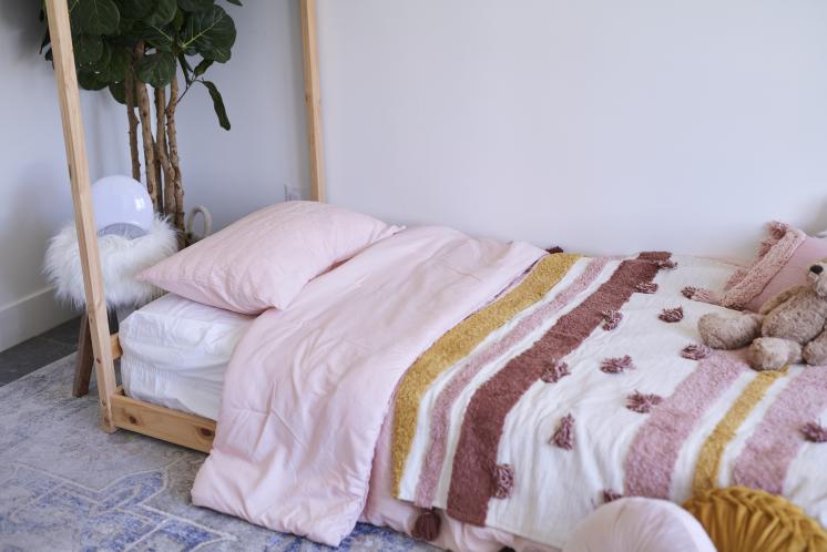 Montessori floor bed in toddlers room covered in pink sheet set