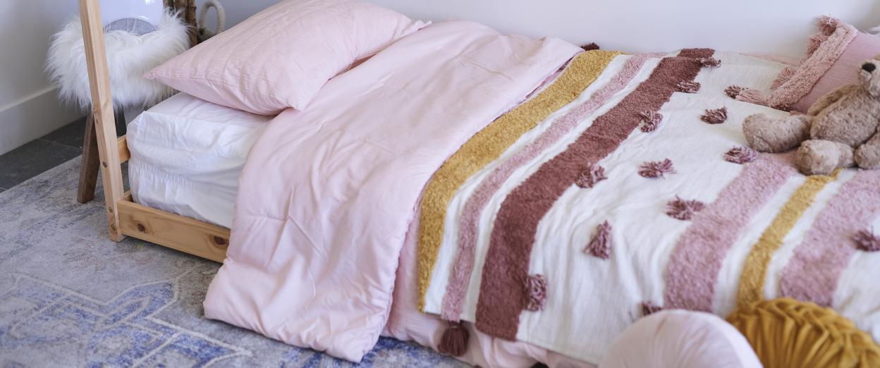 Montessori floor bed in toddlers room covered in pink sheet set