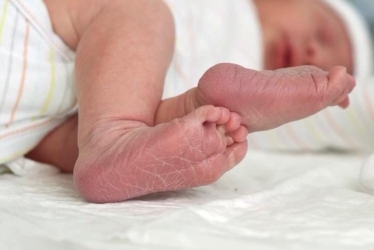 unclose view of newborn baby feet with baby curled to the side