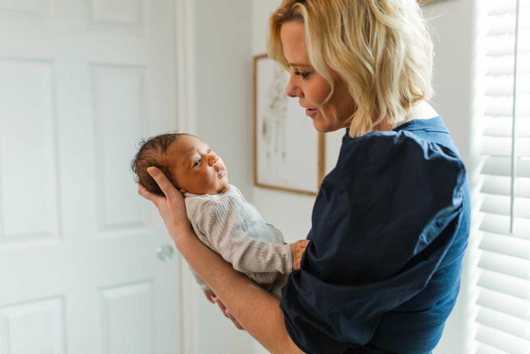 newborn baby staring away as a sleepy cue while being held by Cara