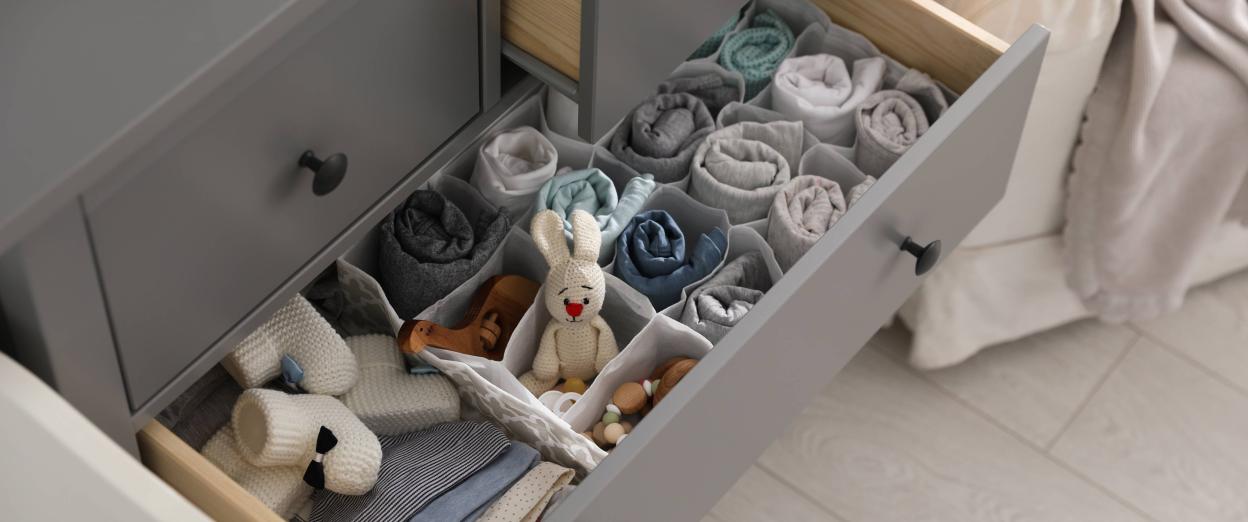 open dresser drawer filled with baby clothes, toys, and accessories neatly organized