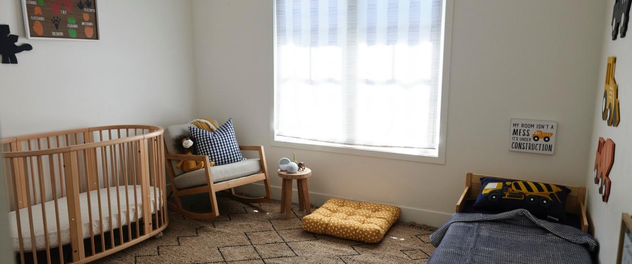 young boys bedroom with crib on one side of the room and a toddler bed on the other side