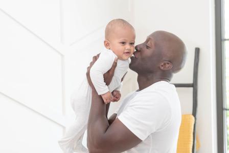 Dad kissing baby on the cheek after getting him out of crib in the morning