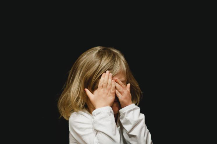 toddler girl covering her eyes in dark room