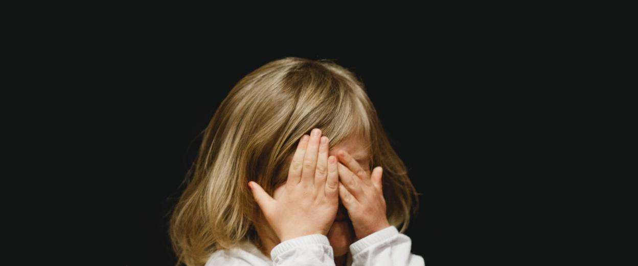 toddler girl covering her eyes in dark room