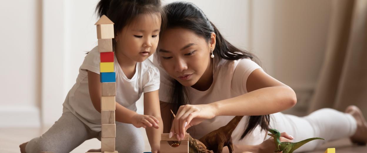 Toddler girl playing blocks on the floor with mom