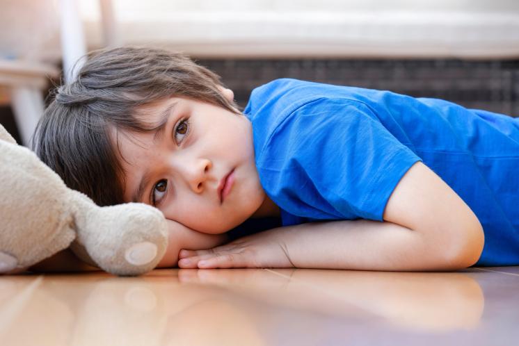 tired toddler gazing into the distance while laying on the floor refusing to nap
