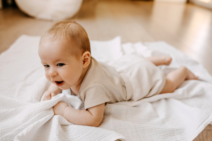 baby doing tummy time on a white blanket during awake time for the 4 to 3 nap transition