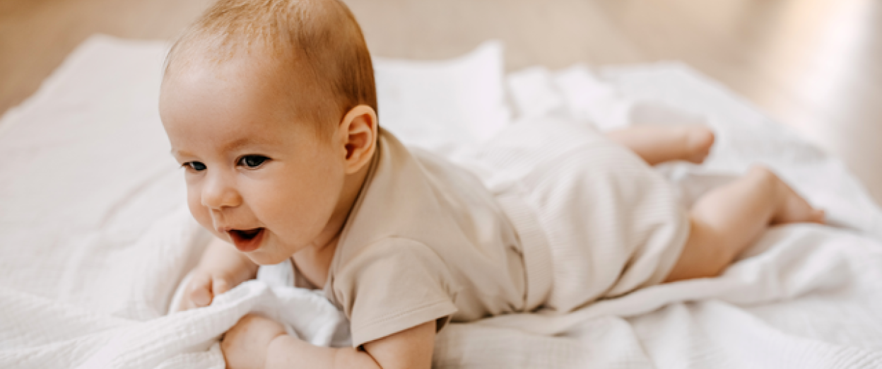 baby doing tummy time on a white blanket during awake time for the 4 to 3 nap transition